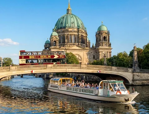 Big Bus Berlin hop on hop off bus crossing a bridge by Berlin Cathedral beside a Spree boat
