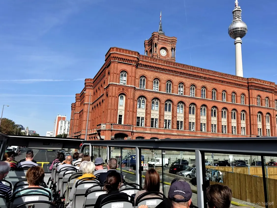 L'hôtel de ville rouge avec sa tour d'horloge et la tour de télévision vus d'un bus hop on hop off de Berlin