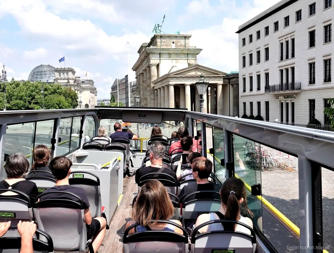 Passatgers a la coberta oberta del bus hop on hop off de Berlín mirant cap a la Porta de Brandenburg
