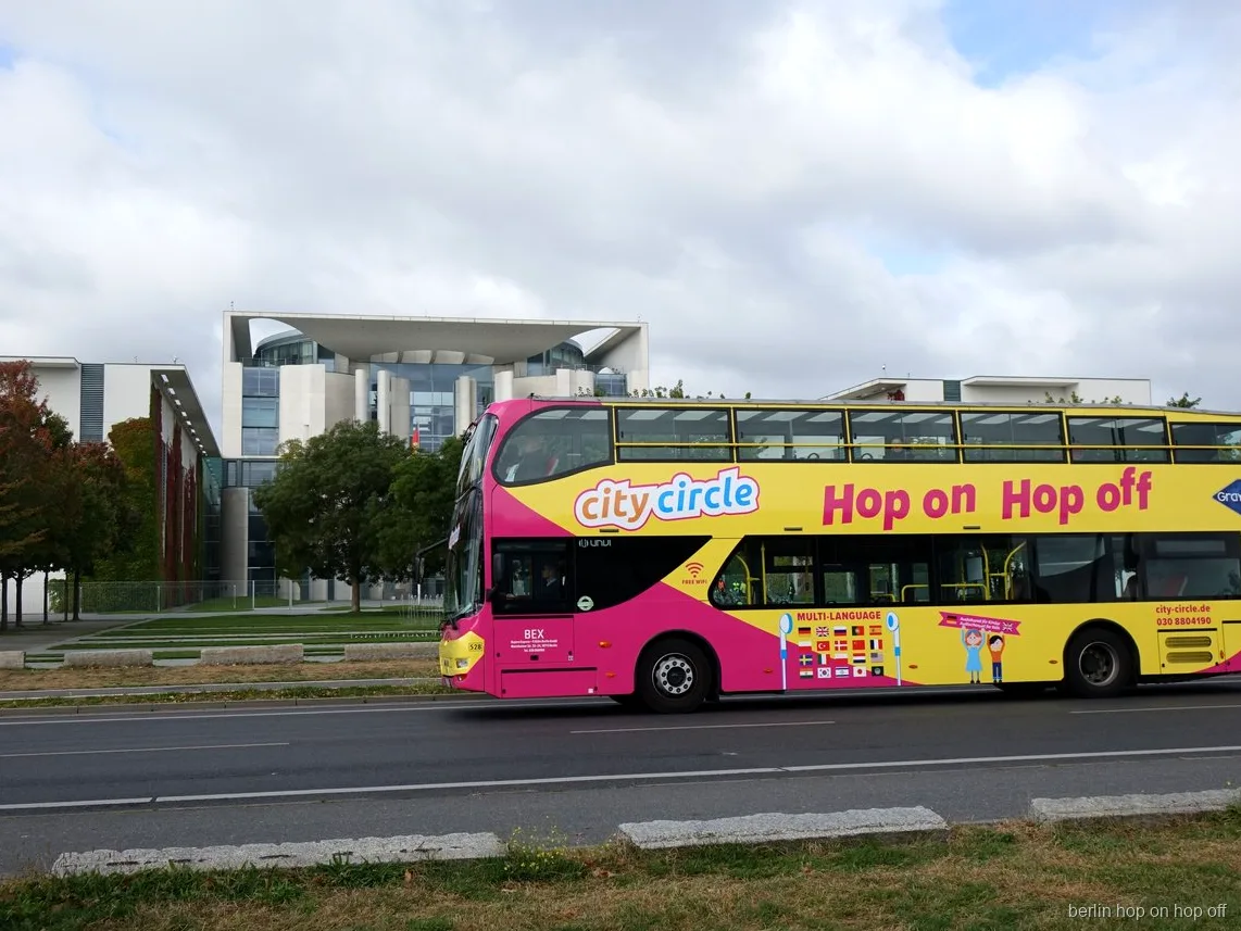 Autobús de dos pisos rosa y amarillo City Circle Berlín hop on hop off pasando por la Cancillería