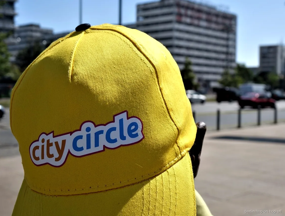 Primer plano de una gorra amarilla City Circle con logotipo en una calle soleada, bus hop on hop off de Berlín