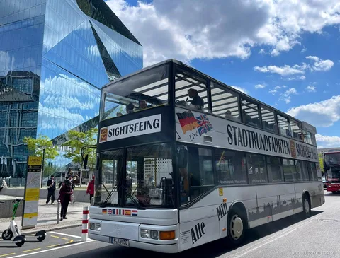 Autobús blanco de dos pisos Stadtrundfahrten Sightseeing del hop on hop off de Berlín junto a un edificio de cristal