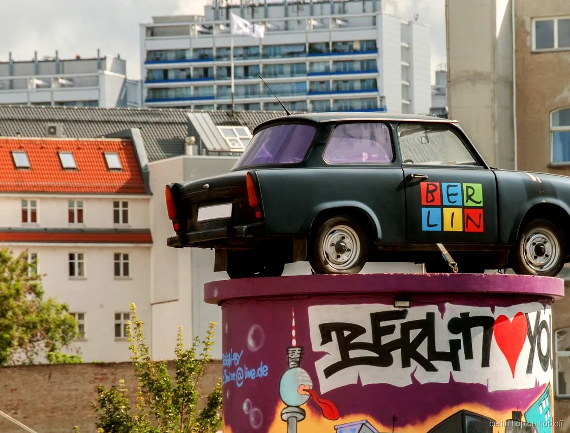 Trabant car on a graffiti column painted with Berlin, seen on the City Sightseeing Berlin hop-on hop-off route
