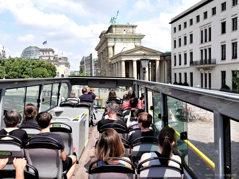 Berlin hop on hop off otobüsünün açık üst katında yolcular Brandenburg Kapısı'na bakıyor