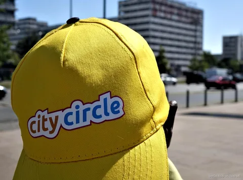 Close up of a yellow City Circle cap with logo on a sunny street, Berlin hop on hop off bus brand