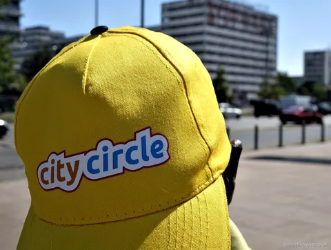 Close-up van een gele City Circle pet met logo op een zonnige straat, Berlijn hop on hop off bus
