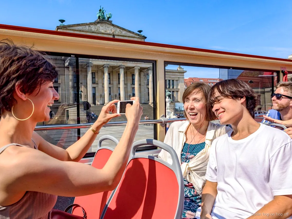 Passagerare på öppet däck i Berlin hop on hop off bussen tar en mobilbild vid Gendarmenmarkt
