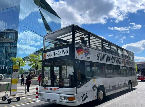 Vit Stadtrundfahrten Sightseeing dubbeldäckare för Berlin hop on hop off bredvid en glasbyggnad