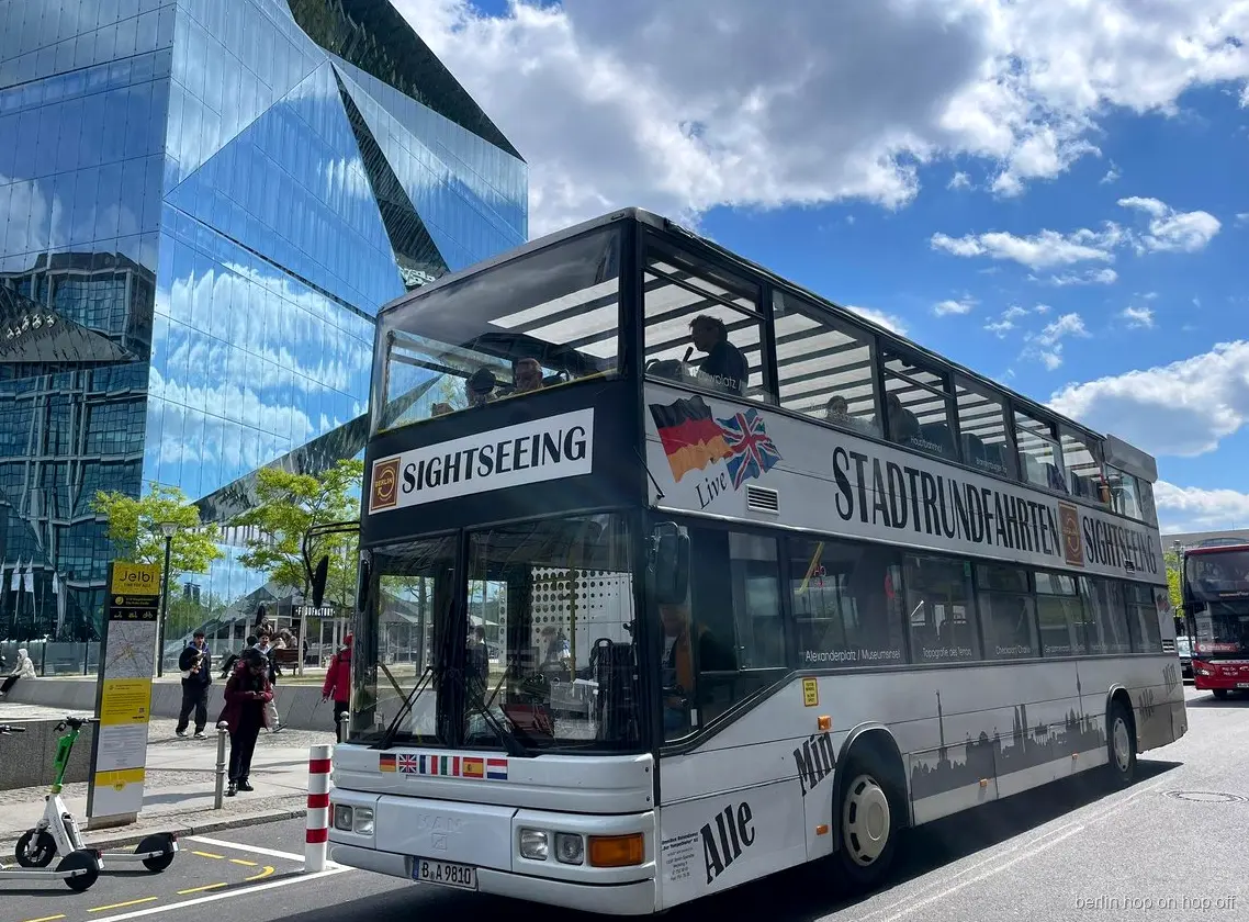 Vit Stadtrundfahrten Sightseeing dubbeldäckare för Berlin hop on hop off bredvid en glasbyggnad