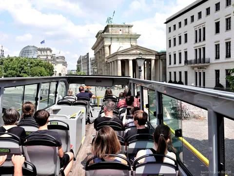 Passeggeri sul piano scoperto del bus hop on hop off di Berlino davanti alla Porta di Brandeburgo