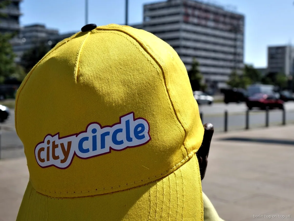 Close-up van een gele City Circle pet met logo op een zonnige straat, Berlijn hop on hop off bus