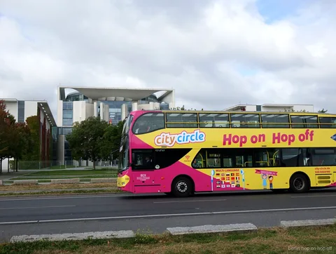 Różowo żółty piętrowy autobus City Circle Berlin hop on hop off mija Kancelarię Federalną