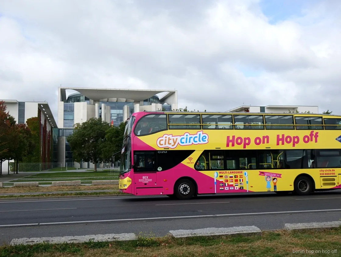 Różowo żółty piętrowy autobus City Circle Berlin hop on hop off mija Kancelarię Federalną