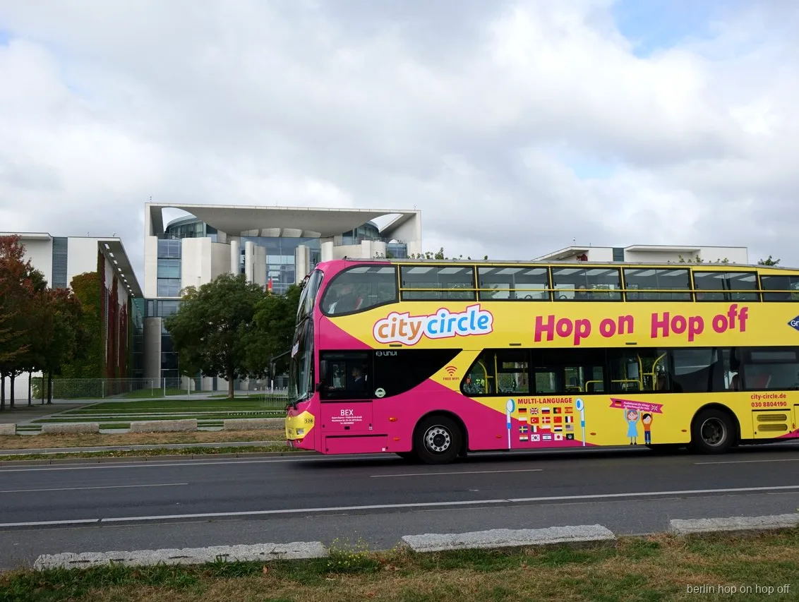Pink og gul City Circle Berlin hop on hop off dobbeltdækkerbus kører forbi Kanzleramt