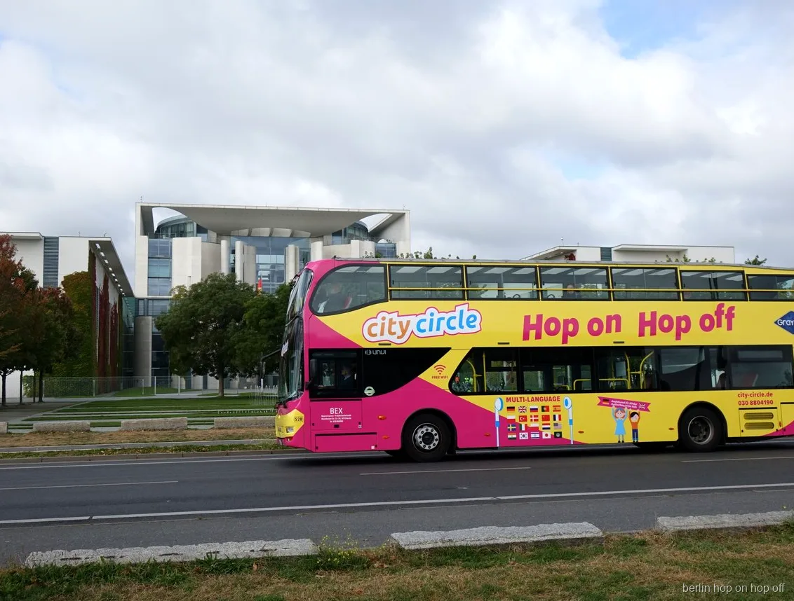 Rosa och gul City Circle Berlin hop on hop off dubbeldäckare passerar förbundskansliet