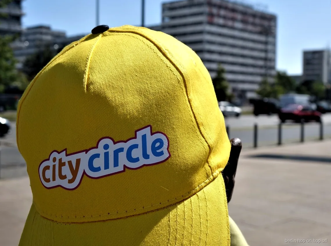 Närbild på en gul City Circle keps med logga på en solig gata, Berlin hop on hop off bussen