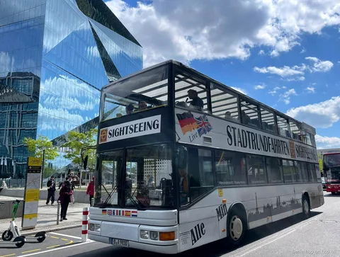 Hvid Stadtrundfahrten Sightseeing dobbeltdækkerbus til Berlin hop on hop off ved en glasbygning