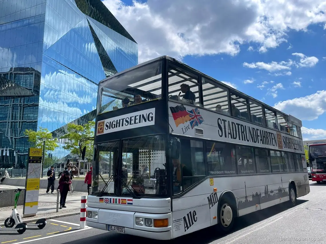 White Stadtrundfahrten Sightseeing double-decker for the Berlin hop on hop off tour beside a glass building