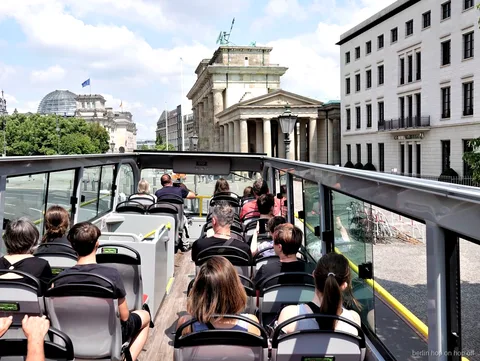 Passagerare på öppet däck i Berlin hop on hop off bussen blickar mot Brandenburger Tor