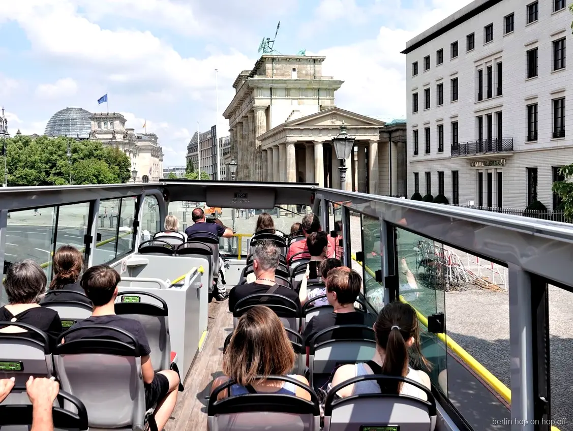 Passagerare på öppet däck i Berlin hop on hop off bussen blickar mot Brandenburger Tor