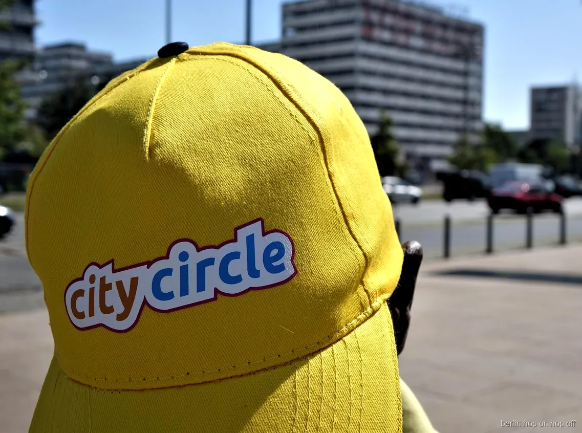 Närbild på en gul City Circle keps med logga på en solig gata, Berlin hop on hop off bussen